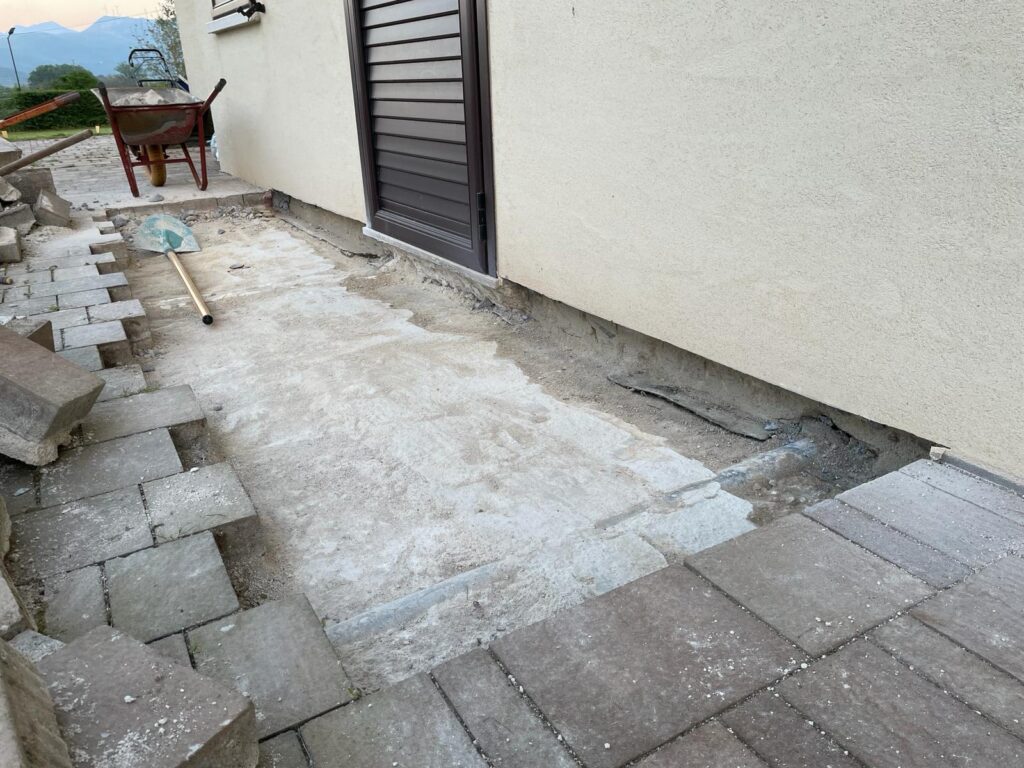 Intervento edile "antimuffa": rimozione di una fascia di marciapiede per impermeabilizzare la muratura